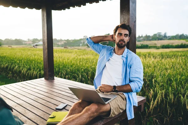 Tarz sahibi, genç, sakallı iş adamı. Günlük giysiler içinde, netbook projesinde çalışıyor. Kırsal kesimde yaz tatilleri boyunca ahşap köşkte oturuyor.