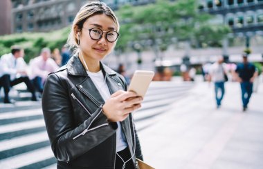 Elektronik kulaklıklı çekici Asyalı turistlerin yarısı ses rehberini dinliyor ve şehir turu sırasında kameraya bakıyor.