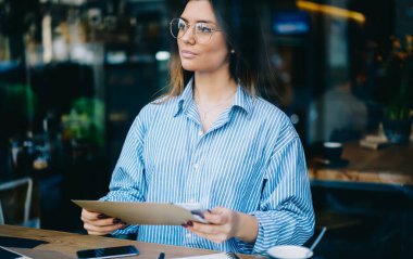 Çizgili tişörtlü genç kız öğrencilerin camından dışarı bakıp mönüde otururken mönüde oturarak teneffüste vakit geçirmeleri.