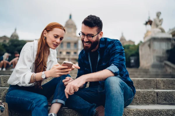 Neşeli hipsterlar modern cep telefonunda 4G kablosuz internet bağlantısı kullanarak komik içerik yayını okuyorlar