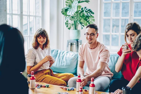 穿着休闲装的年轻人在桌子上享受与薯条的游戏 并在现代公寓里一起度过空闲时间 嬉皮士的家伙与牌玩扑克在时尚的单位 — 图库照片