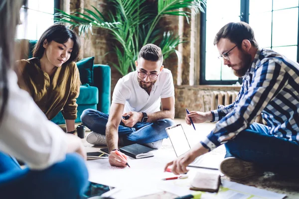 Genç bir grup profesyonel grafik tasarımcısı, beyin fırtınası sırasında plan çizimini tartışmak için konuşuyor. 