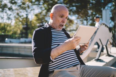 Modern dokunmatik ekrandaki uygulamayı kullanarak ilginç bir ağ videosu izleyen şaşırtıcı erkek seyahat blogcusu