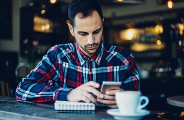 Kafkas erkek blogcu modern akıllı telefon aygıtı kullanarak sosyal medyadaki içerik yayınını aramak için 4G internete bağlanıyor