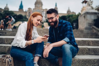 Gülümseyen hipsterlar modern cep telefonunda 4G kablosuz internet bağlantısı kullanarak komik içerik yayını okuyorlar