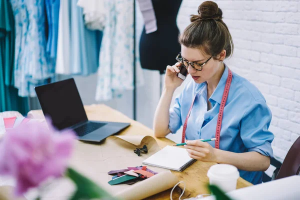 Junge Schneiderin Spricht Mit Kundin Handy Und Macht Sich Notizen — Stockfoto