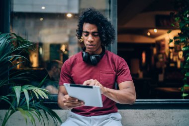 Kulaklıklarla karışık milenyum, modern dokunmatik ped teknolojisinde 4g kablosuz bağlantı kullanarak medya uygulamasının kurulumu ile ilgili web sorununu kontrol ediyor.