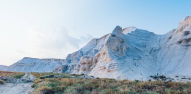 Ustyurt Doğa Koruma Alanı 'nın boş susuz çöl arazisinde yol kenarındaki kayalık dağ manzarası kuru yeşil bitkilerle kaplıdır. 