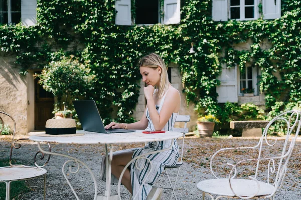 沉思的女工在纽约度暑假时 通过笔记本电脑上网和独自在院子里休息的侧视图 — 图库照片