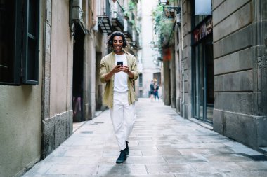 Gülümseyen yakışıklı erkek milenyum müziği akıllı telefon çalma listesine indiriyor teknolojiyle yürüyor ve şehir sokaklarında 4G bağlantısı var