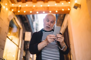  Harika emekli adam internet bankacılığı yapmak için modern akıllı telefon cihazında 4G internet bağlantısı kullanıyor.