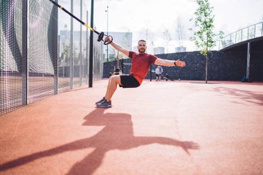 Spor ayakkabılı güçlü bir adam şehirde uzaklaştırma eğitimi alıyor ve hafta sonunu spor sahasında geçirirken başka tarafa bakıyor.