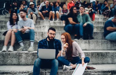 Erkek ve neşeli kadın serbest çalışanlar uzaktan kumanda ile bilgisayar teknolojisi üzerinde çalışırken web projesini tartışıyorlar.
