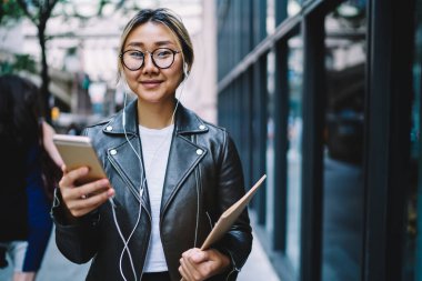 Mutlu milenyum blogcusunun yarım boy portresi eğitim eskiz defteriyle kameraya gülümserken pozitif müzik podcast 'i dinliyor.