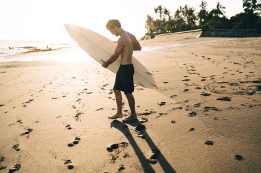 Genç erkek sörfçü, en sevdiği su hobisi olan Karayip Sahili 'nde boş günlerini çalışarak geçiriyor.