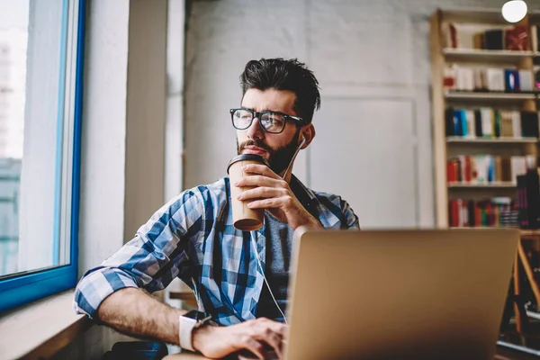 Doordachte Hipster Man Genieten Van Nieuwe Afspeellijst Oortelefoons Drinken Koffie — Stockfoto