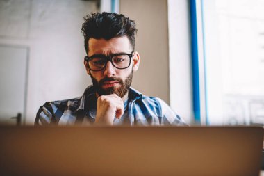 Webinar modern dizüstü oturma masaüstü üniversite kampüsünde, erkek grafik tasarımcı giyim gözlük var bilgisayarda dosya indirme ile sorun mutsuz, izleyen genç ciddi beyaz adamım