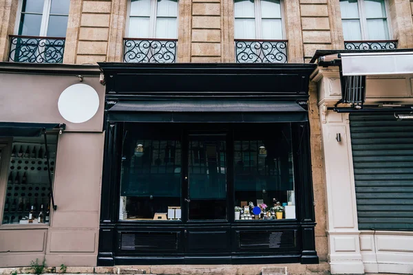 From below of modern shop with goods behind storefront in front of historic building with French balconies in downtown of Bordeaux