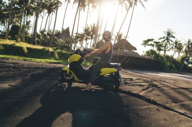 Tanınmayan, koruyucu kask takan ve motosikletin üstünde oturup kumlu sahilde vakit geçiren bir sürü erkek.