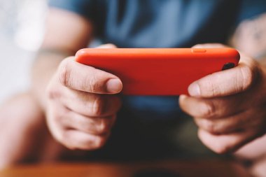 Hafta sonları oyun oynarken kırmızı kutuda cep telefonu tutan isimsiz bir adam yatay konumda