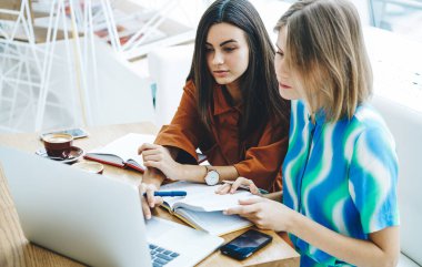 Çok ırklı kız öğrencilerin dizüstü bilgisayarlarını karıştırıp test için hazırlanmalarından ders kitapları, akıllı telefonlar ve kahve bardaklarıyla birlikte oturmalarına kadar.