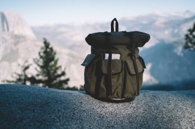 Amerika 'daki Yosemite Ulusal Parkı' ndaki uzak dağların muhteşem sakin manzarasına karşı kayalık kayalıklara yerleştirilmiş bir sırt çantası.