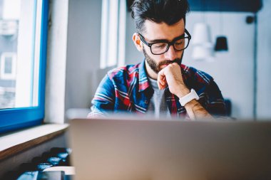 Düşünceli erkek metin yazarı alan, konsantre adam için kablosuz bağlıyken netbook kullanarak yeni Web sayfası oluşturma hakkında düşünme coworking, modern dizüstü bilgisayar ile vakit gözlük