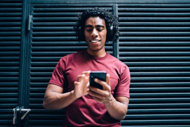 Elektronik kulaklıklı mutlu hipster adam akıllı telefon teknolojisini taradı.