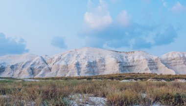 Mavi gökyüzünün altındaki kayalık sıradağların muhteşem manzarası. Su geçirmez çöl vadisindeki ender bulutlar kuru bitkilerle kaplı.