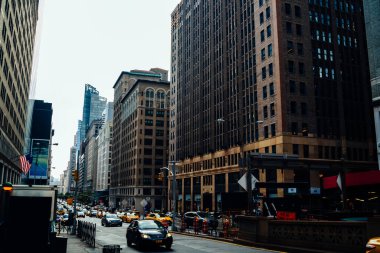 New York şehir merkezindeki yüksek binalar arasında asfalt kaldırım üzerinde giden araba trafiği