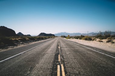 Durgun asfalt yolun yukarısından Amerika 'da güneşsiz bir günde kuru kahverengi vadi boyunca uzanan aralıklı hat.