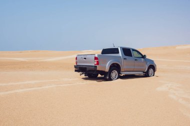 Çölde boş bir arazi aracı güneş ışınları altında ve yaz tatilinde araba kullandıktan sonra kumdaki lastik izleri.