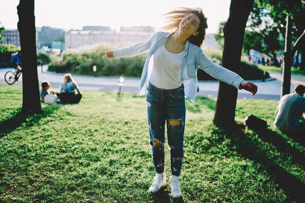 Günlük sokak kıyafetleri giymiş kaygısız bir kız öğrenci. Parkta güneşli bir gün boyunca mutluluk ve özgürlük hissediyor.