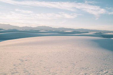 Beyaz Kumlar Ulusal Parkı 'nda gündüz vakti yüksek dağlara ve mavi bulutlu gökyüzüne karşı boş çöl vadisinin görkemli manzarası