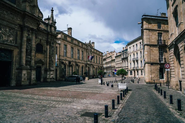 Bordeaux 'nun tarihi şehir merkezinde bulutlu bir günde merkez meydanı yakınlarındaki taş kiliseli antik binalar boyunca asfalt kaldırımlar.
