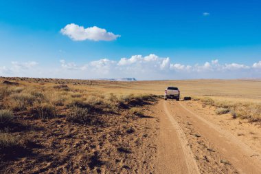 Torysh Toplar Vadisi 'nde boş kumlu yolda tek başına araba sürerken yaz tatilinde havanın güzel olduğu bir günde yolculuk yapmak.