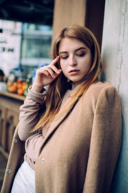 Kendine güvenen, sarı saçlı bir kadın öğle yemeği arasında modern restoranın köşesinde dikilirken aşağı bakıyor ve elini uzatıyor.