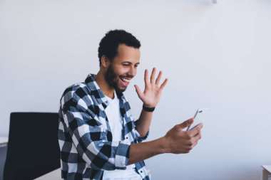 Neşeli sakallı adam cep telefonuyla ofis 4G internetine bağlanan sosyal ağlar için video bloğunu etkiliyor.