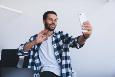  Sosyal medyaya yüklemek için akıllı telefon uygulaması üzerinden fotoğraf çeken mutlu milenyum erkek blog yazarı