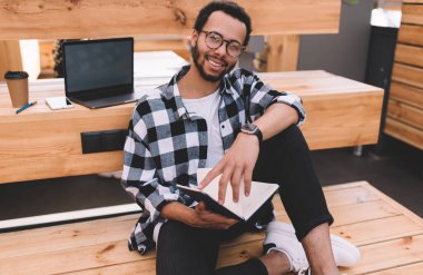  Moda gözlüklü mutlu hippi, eğitim kitabı tutan organizasyonun tadını çıkarıyor.