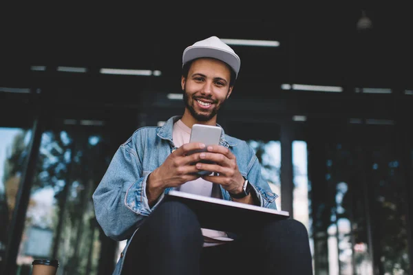 Portrét Veselého Hipster Chlap Drží Smartphone Notebook Usmívá Kameru Zatímco — Stock fotografie