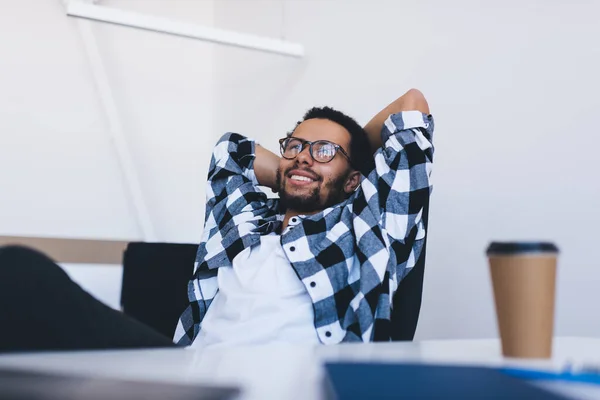 Lazy employee in classic eyewear for vision protection enjoying working lifestyle while resting at table desktop