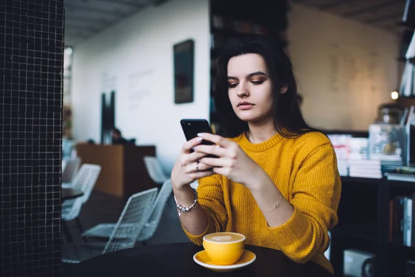 Komoly Fiatal Hölgy Divatos Ruhák Üzenetküldés Mobiltelefon Miközben Asztalnál Kávé — Stock Fotó