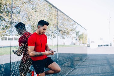 Spor giyim sektöründe beyaz bir adam cep telefonunda kablosuz interneti kullanarak spor bloguna bilgi paylaşmak için kardiyo egzersizleri hakkında yayın yapıyor.