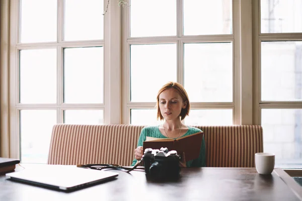 Молода Жінка Сидить Столом Ноутбуком Фотоапаратів Чашкою Гарячого Напою Читає — стокове фото
