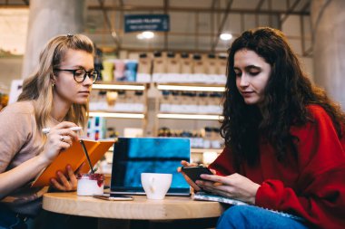 Ciddi meslekdaşlar akıllı telefonlara göz gezdirip not alırken aynı zamanda rahat bir kafede oturup kahve içerek ve internette birlikte çalışarak vakit geçiriyorlar.