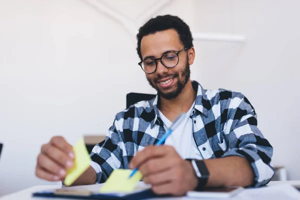 Estudiante Masculino Sonriente Gafas Para Corrección Ojos Tomando Notas Mientras — Foto de Stock