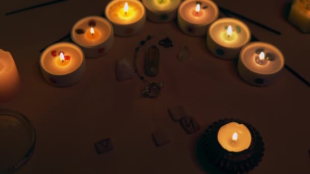 Esoteric seven chakra candles with pendulum, crystals and wooden runes. — Stockvideo