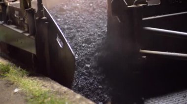 Yeni yol için taşları boşaltıyorum. Asfalt yuvarlama işlemi. Paving makinesi. Gece sahnesi. 