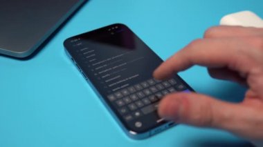 Spotify 'ı bir iPhone' dan aranıyor ve indiriliyor. Mavi arkaplandaki bir telefona bir uygulama indiriliyor. Mykolaiv, Ukrayna, Temmuz 06 2022. 